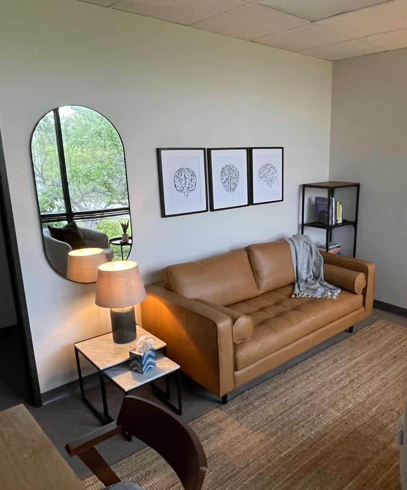 Warm therapy office interior at Fort Worth Therapy Associates featuring tan leather seating, walnut shelving, and natural light